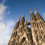 The spires of sagrada família against a blue sky with clouds.